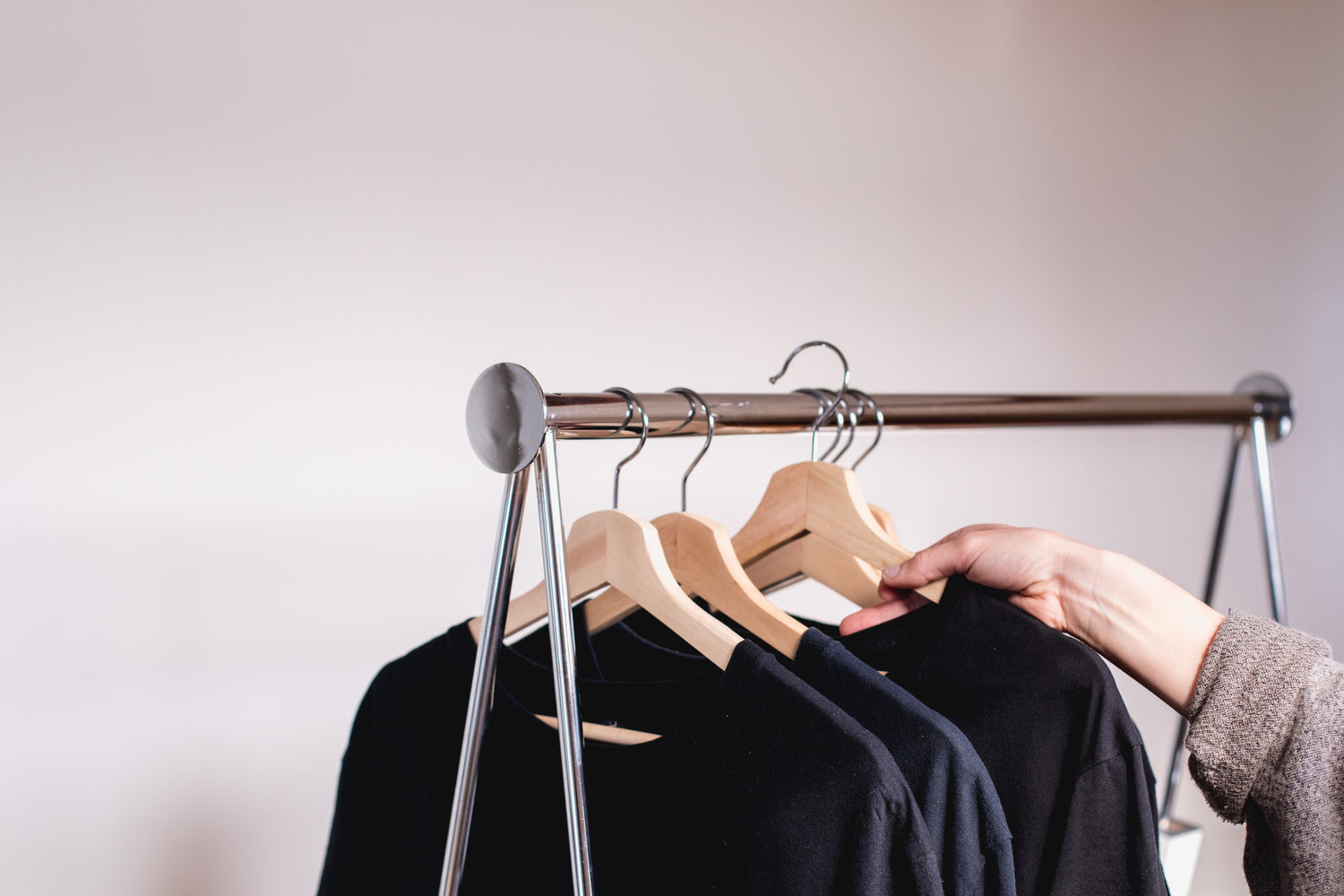 a-hand-removes-a-sweater-from-a-clothing-rack